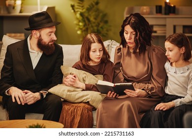 Portrait Of Traditional Jewish Family At Home With Focus On Mother Reading Book