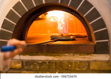 Portrait Of Traditional Stone Oven. Man Hands Baking Pizza