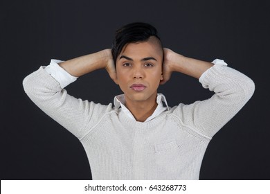 Portrait Of Transgender Woman With Arms Raised Against Black Background