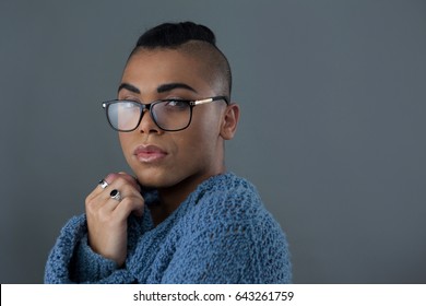 Portrait of transgender woman wearing eyeglasses against gray background