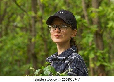 Portrait Of Traveler Smiling Young Woman In Black Cap And Glasses Breathing Fresh Air In The Green Spring Forest.