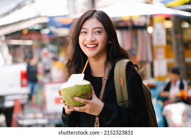 Portrait Of Traveler Young Beautiful Asian Blogger Woman Enjoy Coconut Juice At Street Food Market In Bangkok, Thailand. Holidays, Fun, Travel And People Concept.