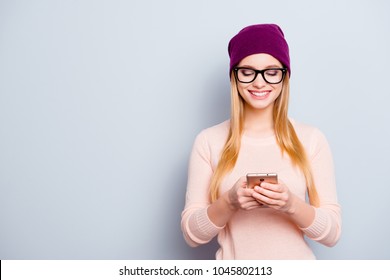 Portrait of trendy style stylish  smart clever excited cute lovely cute sweet teenage girl with long blonde hair using smartphone for sending and receiving messages isolated gray background copy-space