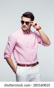 Portrait Of A Trendy Young Man In Sunglasses And Pink Shirt Over Gray Background