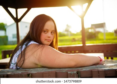 A Portrait of trisomie 21 adult girl outside at sunset