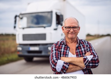 Portrait of a truck driver with crossed arms standing in front of the truck.