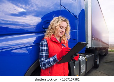 Portrait of truck driver doing paperwork by truck vehicle. Transportation service. - Powered by Shutterstock