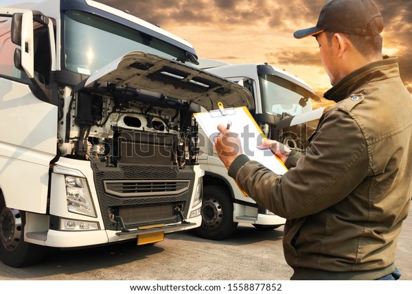 Portrait of truck driver inspecting safety checklist of\
a truck engine 