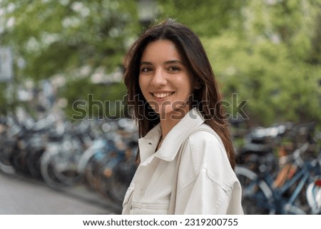 Portrait of Turkish splendid looking young woman confident about bright future on urban street with bicycles in the background