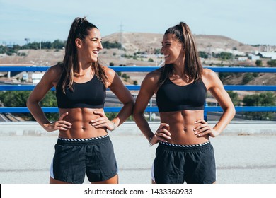 Portrait of twins sisters athletes looking at camera in the street