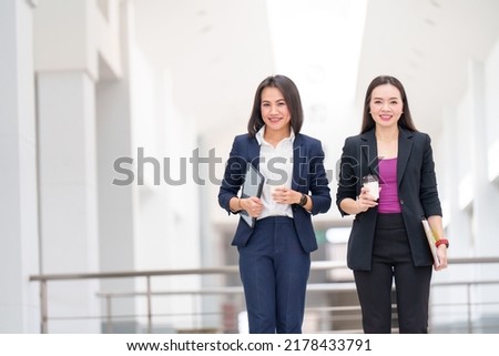 portrait Two Asian businessmen are wearing suits standing in the office building.