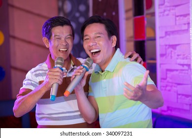 Portrait Of Two Asian Men Enjoying Their Time In Karaoke