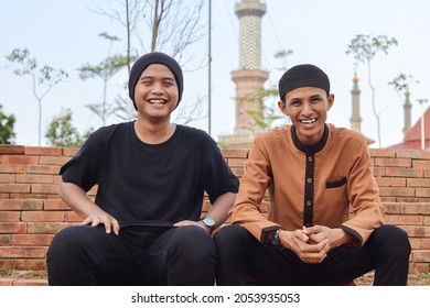 Portrait Of Two Asian Muslim Man Sitting In City Park And Talking To Each Other And Looking At Camera