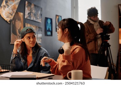 Portrait of two Asian women engaging in thoughtful conversation about an art project in an urban studio - Powered by Shutterstock