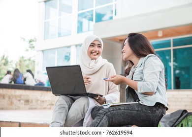 Portrait Of Two Attractive Asian College Student Using Laptop On Campus