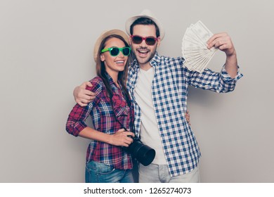 Portrait of two attractive cheerful cheery people husband wife wearing checked shirt showing fan of cash winning international tourism isolated over gray pastel background