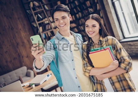 Portrait of two attractive cheerful friends friendship learners hugging taking making selfie practicing at loft industrial interior indoors