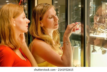 Portrait of an two attractive young women looking at the shop window with jewelry