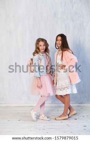Portrait of two beautiful fashionable girl girlfriends in white pink clothes