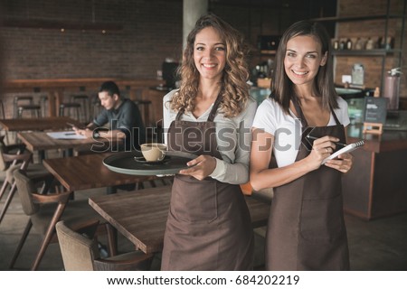 portrait of two beautiful female waitress smiling to camera
