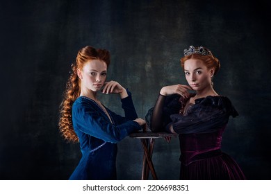 Portrait Of Two Beautiful Women In Image Of Queen And Princess Isolated Over Dark Background. Royal Family. Concept Of Comparison Of Eras, Modernity And Renaissance, Baroque Style, Beauty, History