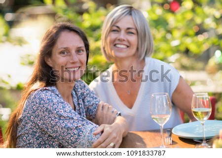 Two women enjoying wine and conversation outdoors