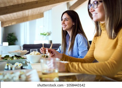 Portrait of two beautiful young women eating japanese food at home.