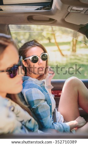 Two young women resting sitting inside of car