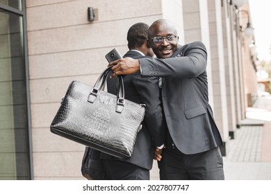 Portrait Of Two Black African American Businessmen In Suits Shaking Hands And Hugging Tightly Outdoors. The Joy Of Meeting Good Friends