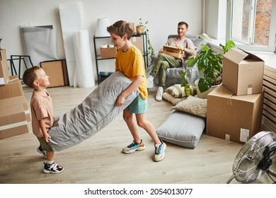 Portrait Of Two Boys Building Pillow Fort In Room With Boxes While Family Moving In To New House, Copy Space