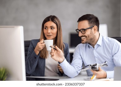 Portrait of two business people working together in  office. Couple teamwork startup concept. They are looking at the drone - Powered by Shutterstock