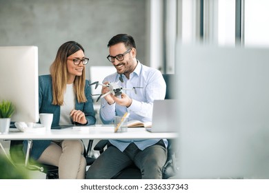 Portrait of two business people working together in  office. Couple teamwork startup concept. They are looking at the drone - Powered by Shutterstock