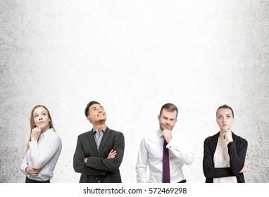 Portrait Of Two Businessmen And Two Businesswomen Thinking Hard While Standing Near A Concrete Wall. Mock Up.