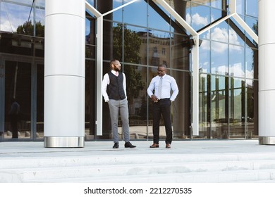 Portrait Of Two Businessmen Walking And Talking In Front Of A Modern Building Exterior. Friendly Meeting Outdoors