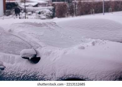 A Portrait Of Two Cars Parked In A Driveway Covered In White Snow During Winter On A Cloudy Day. The Driver Will Have To Clear The Windows Before Driving Or Will Have To Wait For The Snow To Melt.