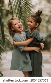 Portrait of two charming smiling girls belonging to different races surrounded by tropical leaves. Friendship, linen clothing, environmental friendliness. High quality photo - Shutterstock ID 2054357363