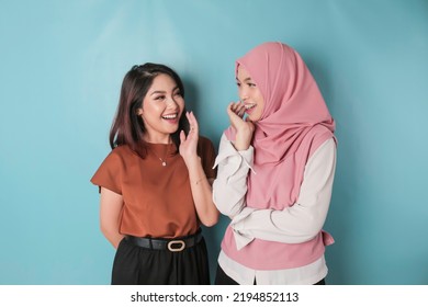 Portrait Of Two Cheerful Asian Women Standing And Laughing, Isolated On Blue Background