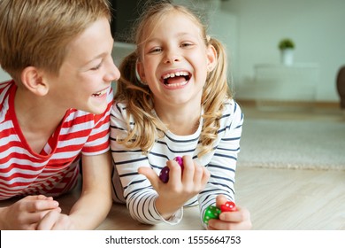 Portrait of two cheerful children laying on the floor and playing emotionally with colorful dices 