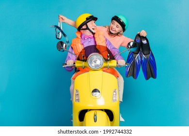 Portrait of two cheerful elderly retired pensioners riding moped holding dive things isolated over bright blue color background - Powered by Shutterstock