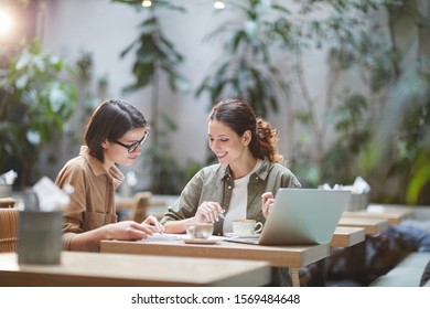 Portrait of two cheerful young omen enjoying work in beautiful outdoor cafe, copy space - Powered by Shutterstock