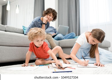 Portrait of two children drawing pictures sitting on carpet in living room with mom watching them from sofa - Powered by Shutterstock