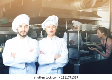 Portrait of two confident chefs posing with crossed arms in professional kitchen - Shutterstock ID 1111791389