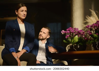 Portrait Of Two Confident People, Colleagues On Business Trip, Caucasian Woman And Man , Business Partners Sitting On Armchair In The Lounge Zone Of A Luxury Hotel