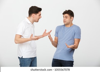 Portrait Of Two Confused Young Men Talking Isolated Over White Background