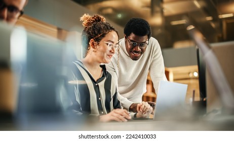 Portrait of Two Creative Colleagues Using Laptop to Discuss Work Project at Office. Young Black Technical Support Specialist Helping Female Customer Relationship Coordinator. Teamwork Concept - Powered by Shutterstock