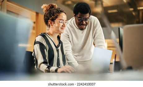 Portrait of Two Creative Colleagues Using Laptop to Discuss Work Project at Office. Young Black Technical Support Specialist Helping Female Customer Relationship Coordinator. Teamwork Concept - Powered by Shutterstock