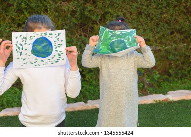 Portrait Of The Two Cute Little Girls Holding The Drawing Earth Globe. Children Draw A Picture Of Earth. GDPR Concept.