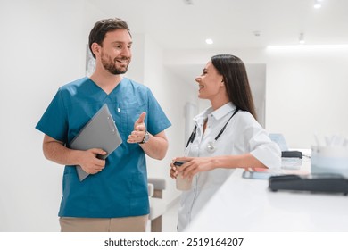 Portrait of two doctors walking standing in hospital corridor hall and talking while have break drink coffee. Two medical specialists discussing the treatment of a patient - Powered by Shutterstock