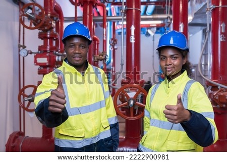 Portrait of two engineer working at system springer prevent fire. Group of African American contractor checking fire sprinkler system, pipe assembly, red fire pipe