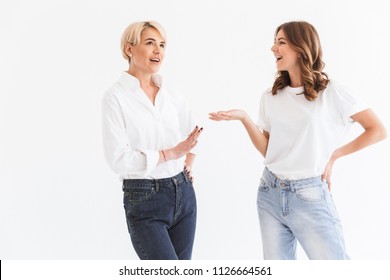 Portrait of two european women adult mother and teenage daughter talking or discussing with interest and gestures standing isolated over white background